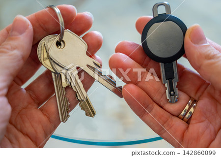 Hands holding traditional metal keys and an RFID key fob together. Concept of transition from mechanical locks to electronic access control and smart security technology Hands holding traditional metal keys and an RFID key fob together. Concept of transition from mechanical locks to electronic access control and smart security technology 142860099