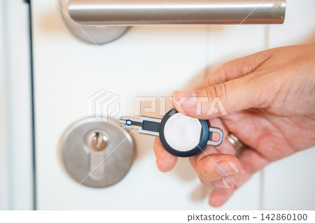 Hand using an RFID key fob to unlock an apartment door with electronic access system. Concept of keyless entry, smart security and modern access control. Hand using an RFID key fob to unlock an apartment door with electronic access system. Concept of keyless entry, smart security and modern access control. 142860100