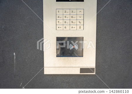 Modern apartment building intercom with keypad and contactless access system. Secure residential access highlights smart building technology and everyday home security. Modern apartment building intercom with keypad and contactless access system. Secure residential access highlights smart building technology and everyday home security. 142860110