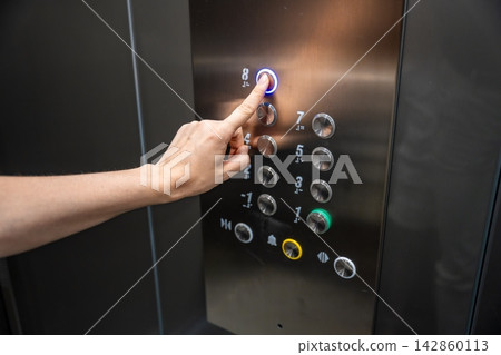 Person pressing the eighth floor button inside a modern elevator. Vertical transportation supports convenient access and efficient movement in residential buildings Person pressing the eighth floor button inside a modern elevator. Vertical transportation supports convenient access and efficient movement in residential buildings 142860113