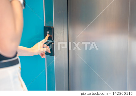 Person pressing elevator call button in modern residential building. Everyday accessibility and vertical transportation improve convenience and mobility Person pressing elevator call button in modern residential building. Everyday accessibility and vertical transportation improve convenience and mobility 142860115