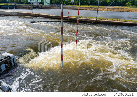 Artificial whitewater slalom course with numbered gates on the Vltava River in Prague Czech Republic. Outdoor kayaking training and canoe slalom concept for water sports and active recreation. Artificial whitewater slalom course with numbered gates on the Vltava River in Prague Czech Republic. Outdoor kayaking training and canoe slalom concept for water sports and active recreation. 142860131