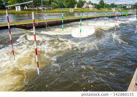 Artificial whitewater slalom course with numbered gates on the Vltava River in Prague Czech Republic. Outdoor kayaking training and canoe slalom concept for water sports and active recreation. Artificial whitewater slalom course with numbered gates on the Vltava River in Prague Czech Republic. Outdoor kayaking training and canoe slalom concept for water sports and active recreation. 142860135
