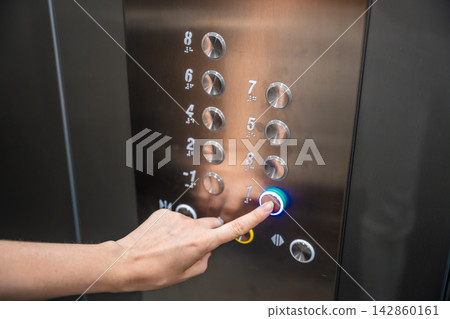Person pressing the first floor button inside a modern residential elevator. Everyday elevator use supports convenient access and efficient movement between building levels Person pressing the first floor button inside a modern residential elevator. Everyday elevator use supports convenient access and efficient movement between building levels 142860161