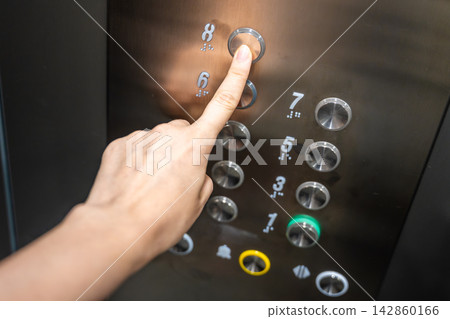 Person pressing the eighth floor button inside a modern elevator. Vertical transportation supports convenient access and efficient movement in residential buildings Person pressing the eighth floor button inside a modern elevator. Vertical transportation supports convenient access and efficient movement in residential buildings 142860166