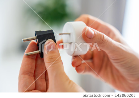 Electrical plug adapters with different socket standards in human hands. International power compatibility concept for travel, electronics and device charging. Electrical plug adapters with different socket standards in human hands. International power compatibility concept for travel, electronics and device charging. 142860205