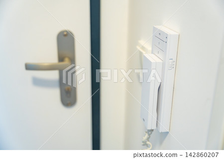 Home intercom system mounted beside an apartment entrance door. Residential access control concept for security, communication and visitor management. Home intercom system mounted beside an apartment entrance door. Residential access control concept for security, communication and visitor management. 142860207