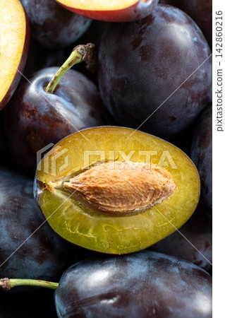 Fresh juicy plums whole and halved with seeds close up texture Fresh juicy plums whole and halved with seeds close up texture 142860216