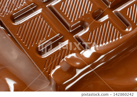 Close up of warm liquid chocolate coating solid chocolate bar Close up of warm liquid chocolate coating solid chocolate bar 142860242