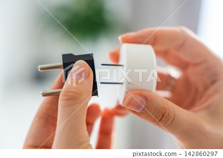 Electrical plug adapters with different socket standards in human hands. International power compatibility concept for travel, electronics and device charging. 142860297