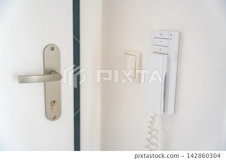 Home intercom system mounted beside an apartment entrance door. Residential access control concept for security, communication and visitor management. Home intercom system mounted beside an apartment entrance door. Residential access control concept for security, communication and visitor management. 142860304
