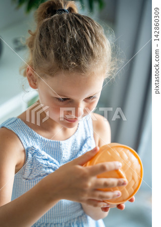 Child prepares to open a surprise squishy toy container at home. Anticipation and curiosity drive the excitement of discovering a hidden collectible. Child prepares to open a surprise squishy toy container at home. Anticipation and curiosity drive the excitement of discovering a hidden collectible. 142860309