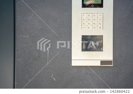 Modern apartment building intercom with keypad and contactless access system. Secure residential access highlights smart building technology and everyday home security. Modern apartment building intercom with keypad and contactless access system. Secure residential access highlights smart building technology and everyday home security. 142860422