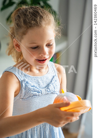 Child reacts with excitement after opening a surprise squishy toy at home. Joy and discovery capture the emotional reward of mystery unboxing. Child reacts with excitement after opening a surprise squishy toy at home. Joy and discovery capture the emotional reward of mystery unboxing. 142860469