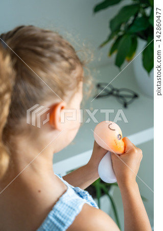 Child squeezes a soft squishy stress relief toy at home. Sensory play supports emotional regulation, relaxation and focus through tactile interaction. 142860477