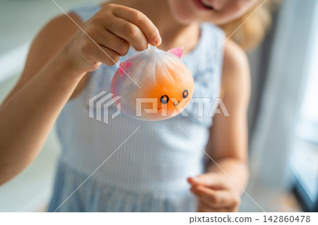 Child holds a cute squishy stress relief toy in hands at home. Sensory play and stress relief encourage relaxation, focus and emotional comfort. Child holds a cute squishy stress relief toy in hands at home. Sensory play and stress relief encourage relaxation, focus and emotional comfort. 142860478