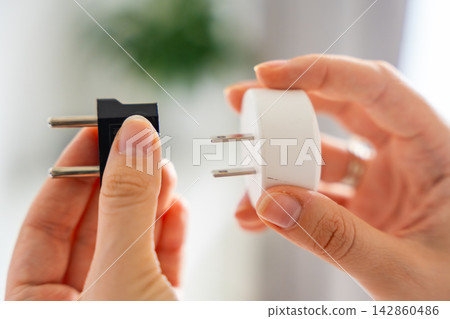Electrical plug adapters with different socket standards in human hands. International power compatibility concept for travel, electronics and device charging. 142860486