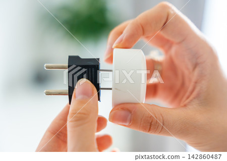 Electrical plug adapters with different socket standards in human hands. International power compatibility concept for travel, electronics and device charging. Electrical plug adapters with different socket standards in human hands. International power compatibility concept for travel, electronics and device charging. 142860487