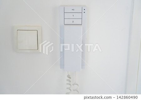 Home intercom system mounted beside an apartment entrance door. Residential access control concept for security, communication and visitor management. Home intercom system mounted beside an apartment entrance door. Residential access control concept for security, communication and visitor management. 142860490