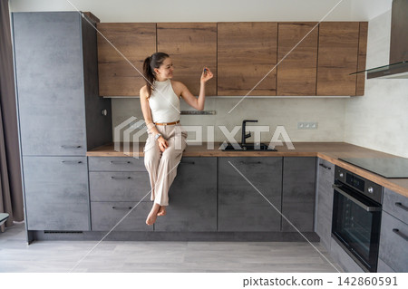 Young woman with apartment keys standing in modern kitchen interior. New beginning and life change after moving into new home concept Young woman with apartment keys standing in modern kitchen interior. New beginning and life change after moving into new home concept 142860591