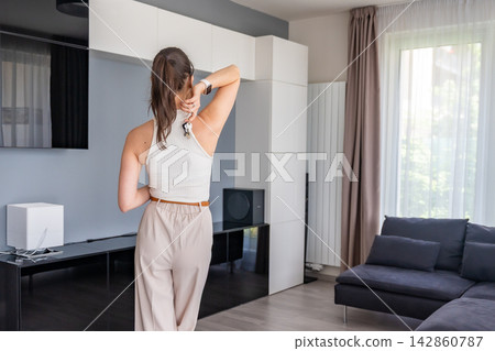 Young woman standing in modern apartment and holding house keys behind her back. Female home ownership and independent real estate achievement concept Young woman standing in modern apartment and holding house keys behind her back. Female home ownership and independent real estate achievement concept 142860787
