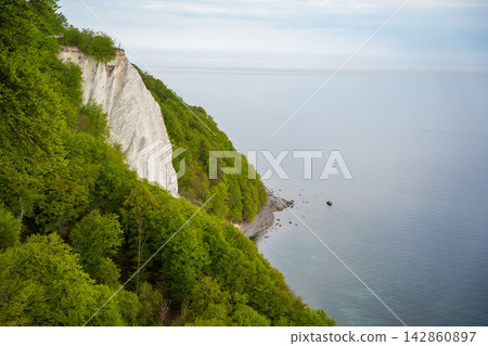 View of famous white chalk cliffs in Jasmund National Park on Rugen island, Germany. Scenic Baltic Sea coastline from forest trail View of famous white chalk cliffs in Jasmund National Park on Rugen island, Germany. Scenic Baltic Sea coastline from forest trail 142860897