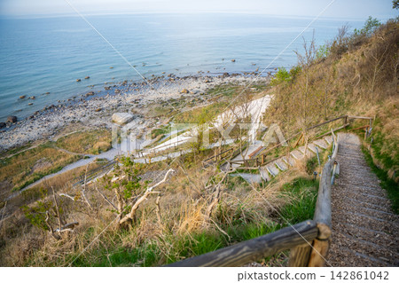 Wooden staircase leading to Baltic Sea beach near Cape Arkona on Rugen island in Germany. Coastal hiking and nature exploration atmosphere. 142861042