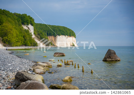 Famous white chalk cliffs and rocky Baltic Sea coastline in Jasmund National Park on Rugen island, Germany. Iconic natural landmark and coastal travel destination concept. Famous white chalk cliffs and rocky Baltic Sea coastline in Jasmund National Park on Rugen island, Germany. Iconic natural landmark and coastal travel destination concept. 142861065