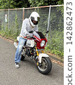 一名男子騎著小型摩托車 142862473