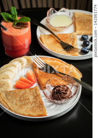 A plate of crepes filled with chocolate spread and topped with banana slices and mint A plate of crepes filled with chocolate spread and topped with banana slices and mint 142863774