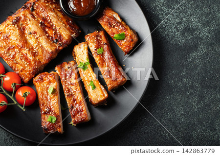 Hot grilled spare ribs from a summer BBQ served on a plate with sauce. Top view. Copy space Hot grilled spare ribs from a summer BBQ served on a plate with sauce. Top view. Copy space 142863779