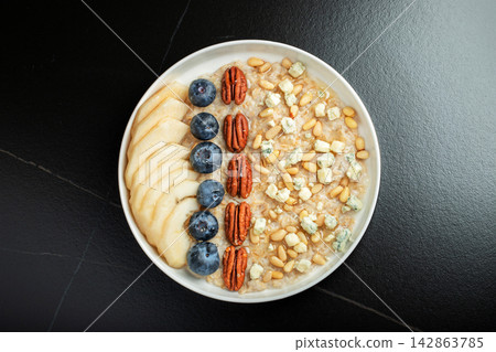 Oatmeal. Bowl of oatmeal porridge with blackberry, bananas and chia seeds on gray concrete old table background. Top view in flat lay style. Natural ingredients. Hot healthy breakfast and diet food Oatmeal. Bowl of oatmeal porridge with blackberry, bananas and chia seeds on gray concrete old table background. Top view in flat lay style. Natural ingredients. Hot healthy breakfast and diet food 142863785