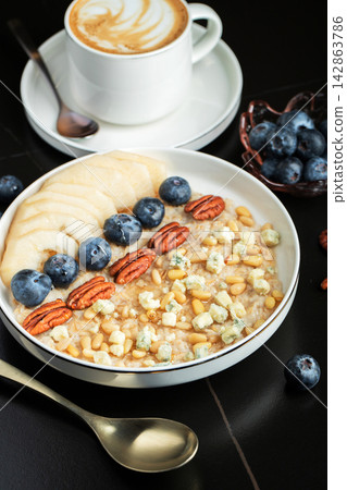 Oatmeal. Bowl of oatmeal porridge with blackberry, bananas and chia seeds on gray concrete old table background. Top view in flat lay style. Natural ingredients. Hot healthy breakfast and diet food Oatmeal. Bowl of oatmeal porridge with blackberry, bananas and chia seeds on gray concrete old table background. Top view in flat lay style. Natural ingredients. Hot healthy breakfast and diet food 142863786