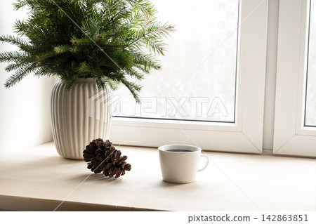 Coffee cup with pine branches on windowsill Coffee cup with pine branches on windowsill 142863851