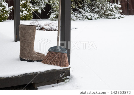Winter boots and broom on snowy porch Winter boots and broom on snowy porch 142863873