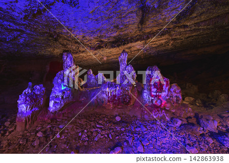 Black Light Illuminated Stalagmites in Cave with Graffiti and Rocky Floor Black Light Illuminated Stalagmites in Cave with Graffiti and Rocky Floor 142863938