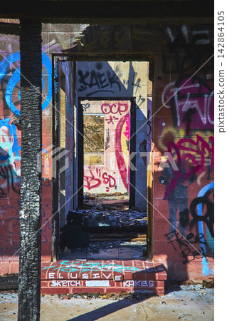 Graffiti Covered Doorway and Ruins in Abandoned Building with Sunlit Debris Graffiti Covered Doorway and Ruins in Abandoned Building with Sunlit Debris 142864105