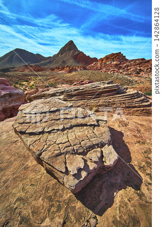 Layered Sandstone Formations Red Desert Landscape and Mountain Peaks Under Blue Sky 142864128