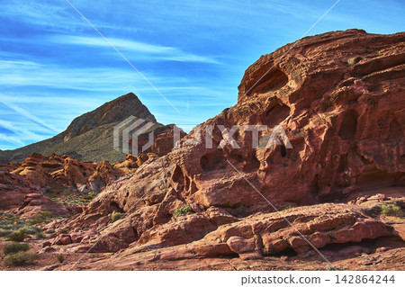 Red Rock Formations and Mountain Peak Under Blue Sky in Desert Landscape Red Rock Formations and Mountain Peak Under Blue Sky in Desert Landscape 142864244