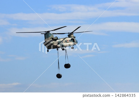 A CH-47J helicopter of the Japan Air Self-Defense Force flies during cargo hoisting training. A CH-47J helicopter of the Japan Air Self-Defense Force flies during cargo hoisting training. 142864335