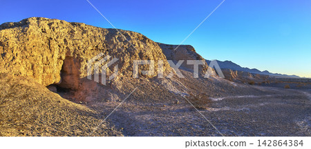 Panorama of Sunlit Fossil Bed Cliffs and Desert Plain at Golden Hour 142864384