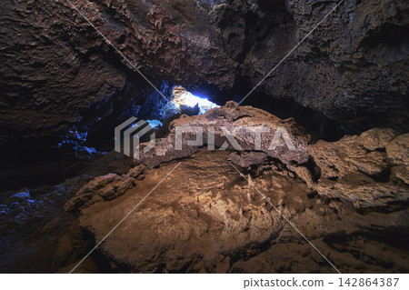 Lava Tube Interior With Volcanic Rock Formations And Natural Light In Desert Cave Lava Tube Interior With Volcanic Rock Formations And Natural Light In Desert Cave 142864387