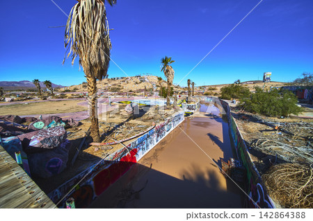 Abandoned Lake Dolores Water Park Graffiti Palm Trees and Desert Landscape California Abandoned Lake Dolores Water Park Graffiti Palm Trees and Desert Landscape California 142864388