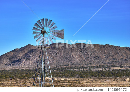 Windmill and Rocky Hills under Clear Blue Sky in Mojave California Desert Windmill and Rocky Hills under Clear Blue Sky in Mojave California Desert 142864472