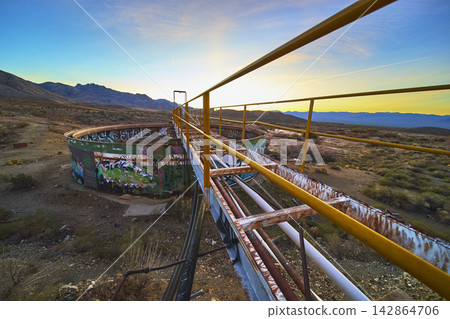 Abandoned Industrial Catwalk and Graffiti Covered Tank in Mojave Desert at Sunset Abandoned Industrial Catwalk and Graffiti Covered Tank in Mojave Desert at Sunset 142864706