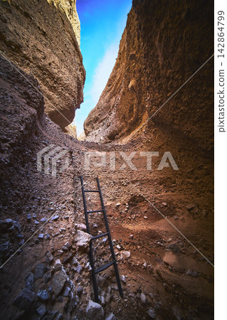 Ladder in Rugged Slot Canyon with Blue Sky and Rocky Trail Arizona Ladder in Rugged Slot Canyon with Blue Sky and Rocky Trail Arizona 142864799