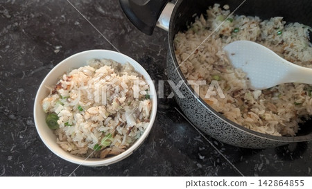 Serving homemade cooked mackerel rice with green onions into a bowl Serving homemade cooked mackerel rice with green onions into a bowl 142864855