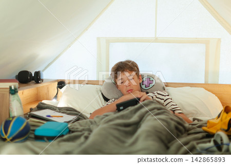 Boy resting in bed playing on tablet Boy resting in bed playing on tablet 142865893