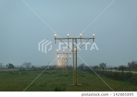 Runway approach lights in foggy landscape Runway approach lights in foggy landscape 142865895