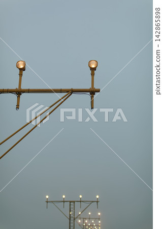 Airport runway approach lights against evening sky Airport runway approach lights against evening sky 142865898
